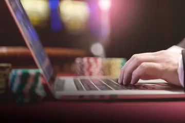 Um dealer profissional de smoking cumprimentando jogadores na mesa de roleta, simbolizando a autêntica sensação de cassino ao vivo no 7GAME SBET.